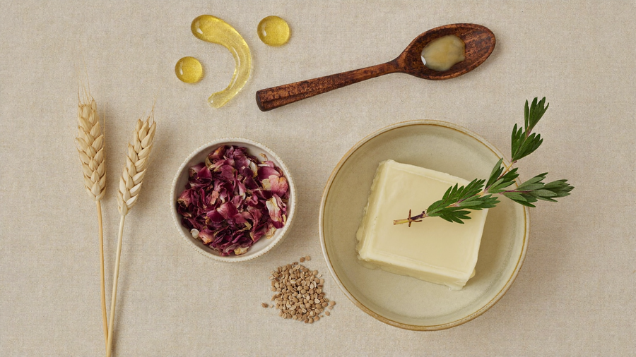 Ingrédients naturels certifiés COSMOS NATURAL : beurre de karité, romarin, blé et vitamine E sur fond de lin beige